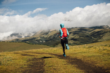 Poster - Fitness woman runner running at high altitude grassland mountain top road