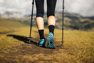 Poster - Fitness woman legs walking on high altitude grassland mountain road