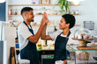 © oneinchpunch - Bakery, happy portrait of hispanic black man and woman in cafe ready for serving pastry, coffee and baked foods - Confident waiter barista by counter for service, help and welcome in a coffee shop