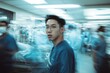 © felix_brönnimann - Dynamic hospital scene featuring a focused young male healthcare professional amidst busy medical staff, conveying urgency and dedication in a fast-paced environment.