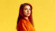 © master1305 - Side view portrait of young serious woman looking at camera, deep in thought, wearing vibrant orange outfit. Confidence. Concept of human emotions, facial expression, lifestyle