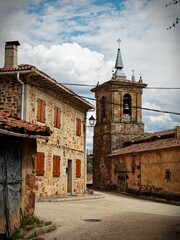 Wall Mural - Rustic village street with stone buildings and church tower.