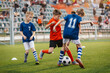 © matimix - Group of Boys Soccer Teams Competing For The Ball During A Football Match. Kids Play Sports In the Stadium. Happy Children Play Soccer Ball on Grass Pitch. Kids in Red and Blue Football Teams in Match