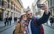 © Jani's Stocks - Smiling tourist couple taking a selfie while exploring a city, capturing joyful travel memories together.