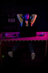 Vertical full body photo of cute lovely nice girl relax hands behind head play gamer computer laptop modern technology indoors late night