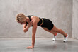© khmelev - Young sporty active woman wear sportswear standing in plank pose with arm resting on opposite shoulde doing yoga fitness training workout stretching core push up pushup exercise in gym space indoors.
