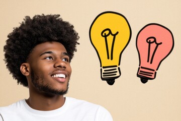 A young man with afro hairs smiling and looking up at two lightbulbs - Technology