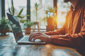 Asian casual businessman typing on a laptop computer working from home.