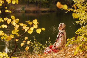 a girl in a national Chuvash costume by a pond in the autumn forest, filmed in the evening light