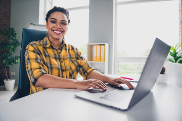 Photo of attractive young woman working laptop wear yellow plaid shirt comfortable modern office loft room interior indoors workspace