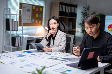 Asian businesspeople working and brainstorming with digital tablet and data charts at office