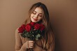 © MUdaylah - Beautiful young woman with bouquet of red roses on brown background. Valentine's Day celebration with generative ai