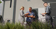 © StockMediaSeller - A technician uses a tablet to demonstrate heat pump functions to a couple beside the outdoor unit.