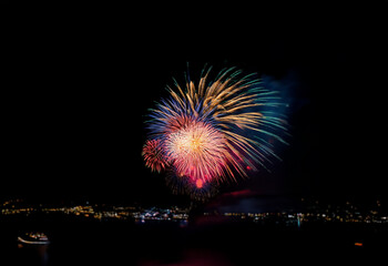 Poster - A colorful display of fireworks explodes against a dark night sky, isolated against a backdrop of city lights.