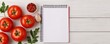 © Chananporn - Fresh tomatoes, herbs, and a blank notepad on a wooden table, ideal for cooking notes.