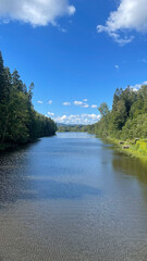 Trees on both side of a lake with blue sky a summer day in Norway