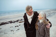 © Marko Geber - Senior couple walking on the beach in winter coats