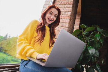 Portrait of nice young girl sit window use laptop open mouth wear yellow sweater loft interior flat indoors