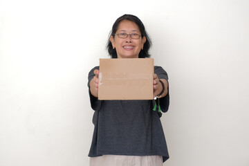 A middle-aged woman is holding a cardboard box with her two hands and smiling