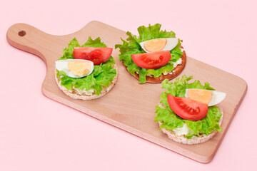 Wall Mural - Rice Cake Sandwiches with Tomato, Lettuce and Egg on Wooden Cutting Board. Easy Breakfast. Diet Food. Quick and Healthy Sandwiches. Crispbread with Tasty Filling. Healthy Dietary Snack