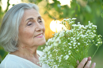 Wall Mural - Portrait of a beautiful elderly woman with a bouquet of flowers in the park