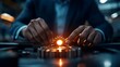© DIAHIMAGESNEW - A man's hands carefully place a gear into a chain of gears, a glowing light illuminates the center of the chain.