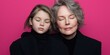 © BOJOShop - Close up Portrait of Grandmother and Granddaughter Hugging with Eyes Closed Against Pink B