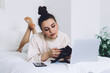 © BullRun - Pensive woman checking wallet while relaxing in bed