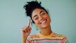 © Fotograf - A happy woman with curly hair smiling and pointing her finger upwards, possibly indicating excitement or optimism