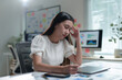 ©  NCST Studio - Tired asian businesswoman suffering from headache while working using laptop computer in office