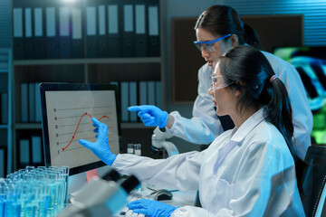 Wall Mural - two scientists wearing lab coats and safety glasses analyzing data displayed on a computer screen in
