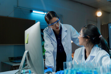 Wall Mural - two scientists are working late in a laboratory, illuminated by the glow of their computer screen as