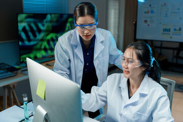 Wall Mural - two female scientists wearing lab coats and safety glasses working together on medical research usin