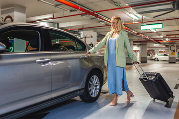 Woman walking in the underground garage with luggage.