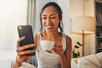 Canvas Print - Morning coffee, phone and happy woman in bedroom for social media, scroll and text message in home. Mobile, girl and drink tea in bed to watch video, reading blog or download app for news on internet