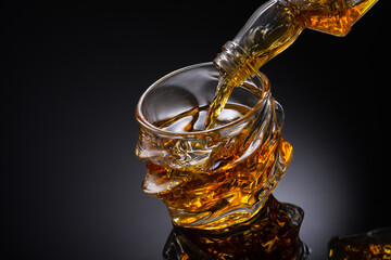 Wall Mural - Glass of whiskey with ice cubes on black background. As whiskey is poured from the bottle into the glass