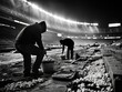 © DachAI - Nighttime workers in an empty stadium, silhouetted against stadium lights, emphasize the essential behind-the-scenes efforts needed for flawless public events.