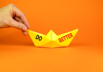 Do better symbol. Concept words Do better on beautiful yellow paper boat. Beautiful orange paper background. Businessmen hand. Business and do better concept. Copy space.