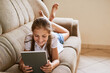 © Nikish Hiraman/peopleimages.com - Happy, sofa and child with tablet in home for online learning, watching movies and internet videos. Family, living room and young girl relax on digital tech for games, streaming cartoons and website