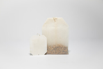 single tea bag standing up with blank label on white background