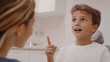 © Bonsales - During a dental checkup, a young boy gestures and speaks to the dentist