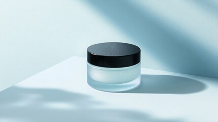Aufkleber - A glass jar of cream with a black lid is on a white surface. Sunlight shines through a window, casting shadows on the surface.