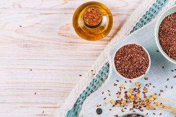 Canvas Print - Brown linen seeds, flaxseed vegetable oil on white wooden background. Healthy super food top view, flat lay with copy space