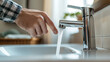 © Daniel - Closeup of Hand Turning on Modern Bathroom Faucet with Water Flowing