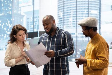 Real estate agent advising clients on an office leasing contract, presenting a layout blueprint of the new space for rental. Planning a business headquarters relocation. Property investing.