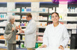 © JackF - At pharmacy, friendly young female apothecary waiting for customers and invites them with gesture go to department of therapeutic cosmetics and sunscreens.