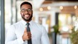 © LifeMedia - The image features a smiling professional man in a white shirt and black tie, giving a thumbs-up gesture, exuding confidence in a brightly lit office setting.