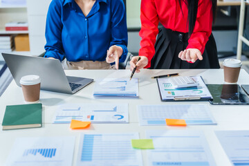 Two young female business consultants work on startup, collaborating on mobile app development social media strategies. whiteboards, documents, they aim to build a successful e-commerce business.