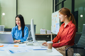 Two young female business consultants work on startup, collaborating on mobile app development social media strategies. whiteboards, documents, they aim to build a successful e-commerce business.