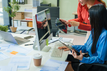Two young female business consultants work on startup, collaborating on mobile app development social media strategies. whiteboards, documents, they aim to build a successful e-commerce business.
